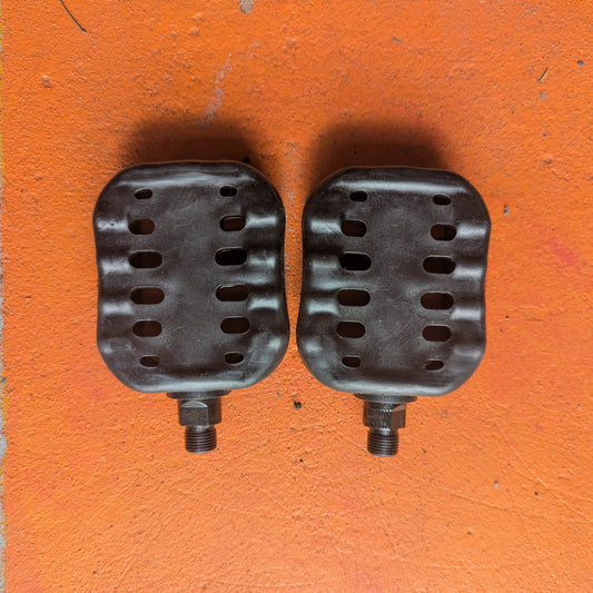 A pair of metal beach cruiser style bicycle pedals with a textured surface, photographed on a plain background.