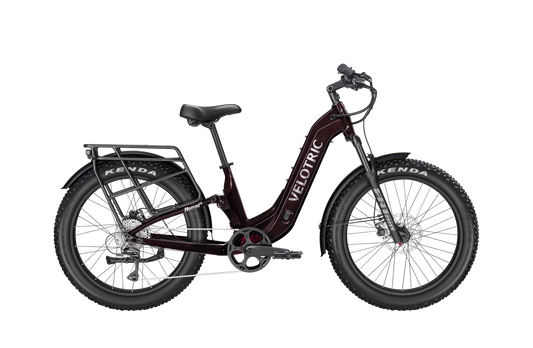 A black Velotric Nomad 2X eBike with fat tires, front suspension fork, integrated battery, and rear cargo rack, shown in a side profile against a white background.